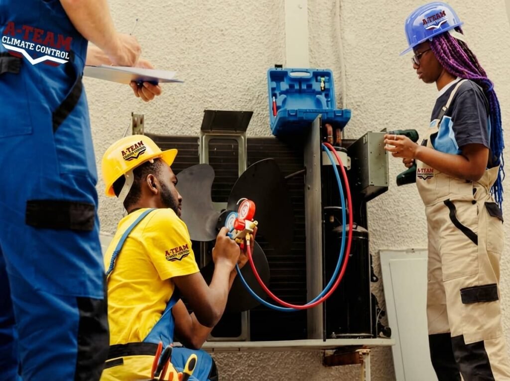 Three HVAC technicians working on an outdoor air conditioning unit, with one technician using refrigerant gauges while others observe and take notes.